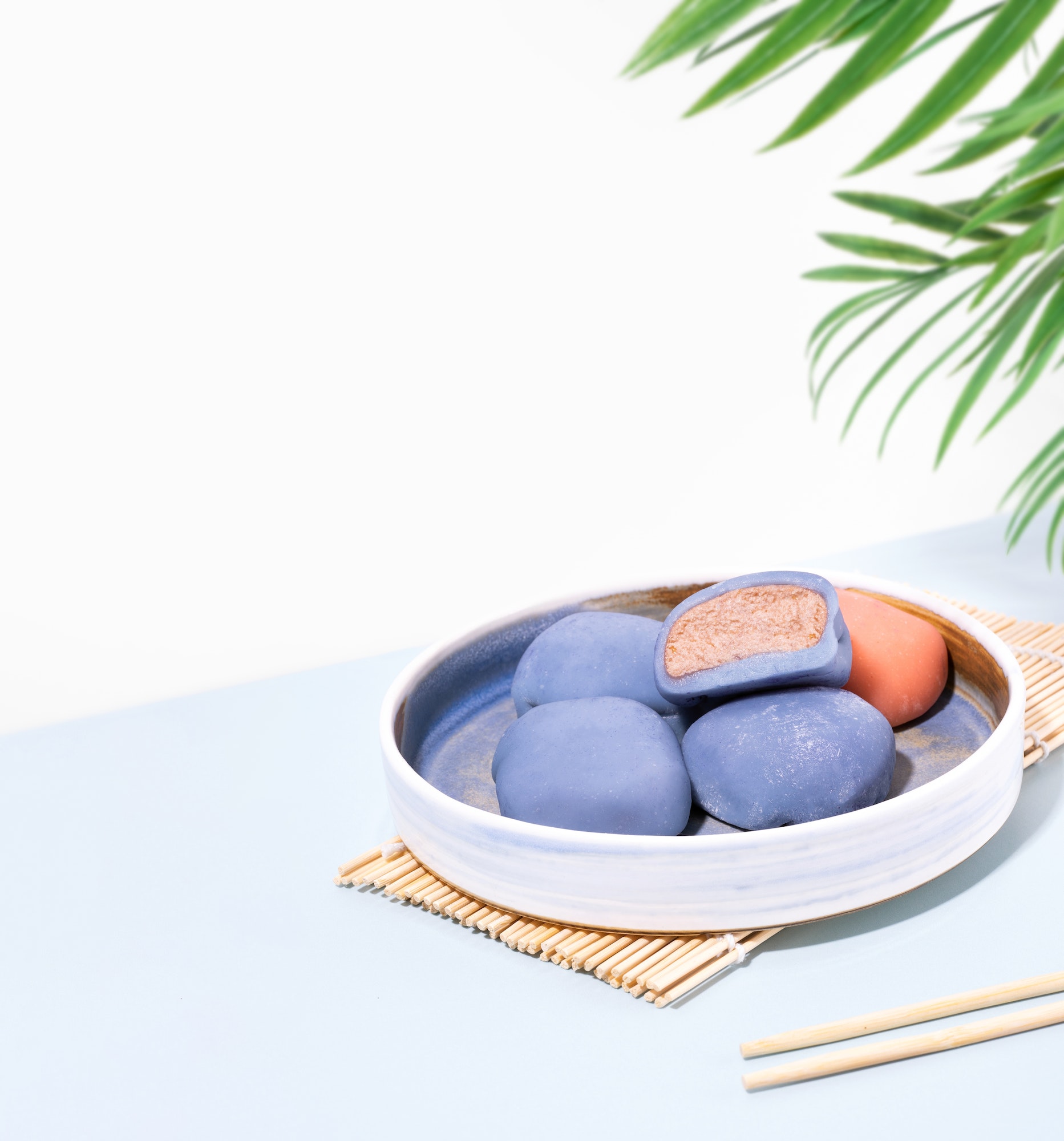 Concept of a traditional Japanese dessert on a blue table. A plate of Japanese mochi with chopsticks