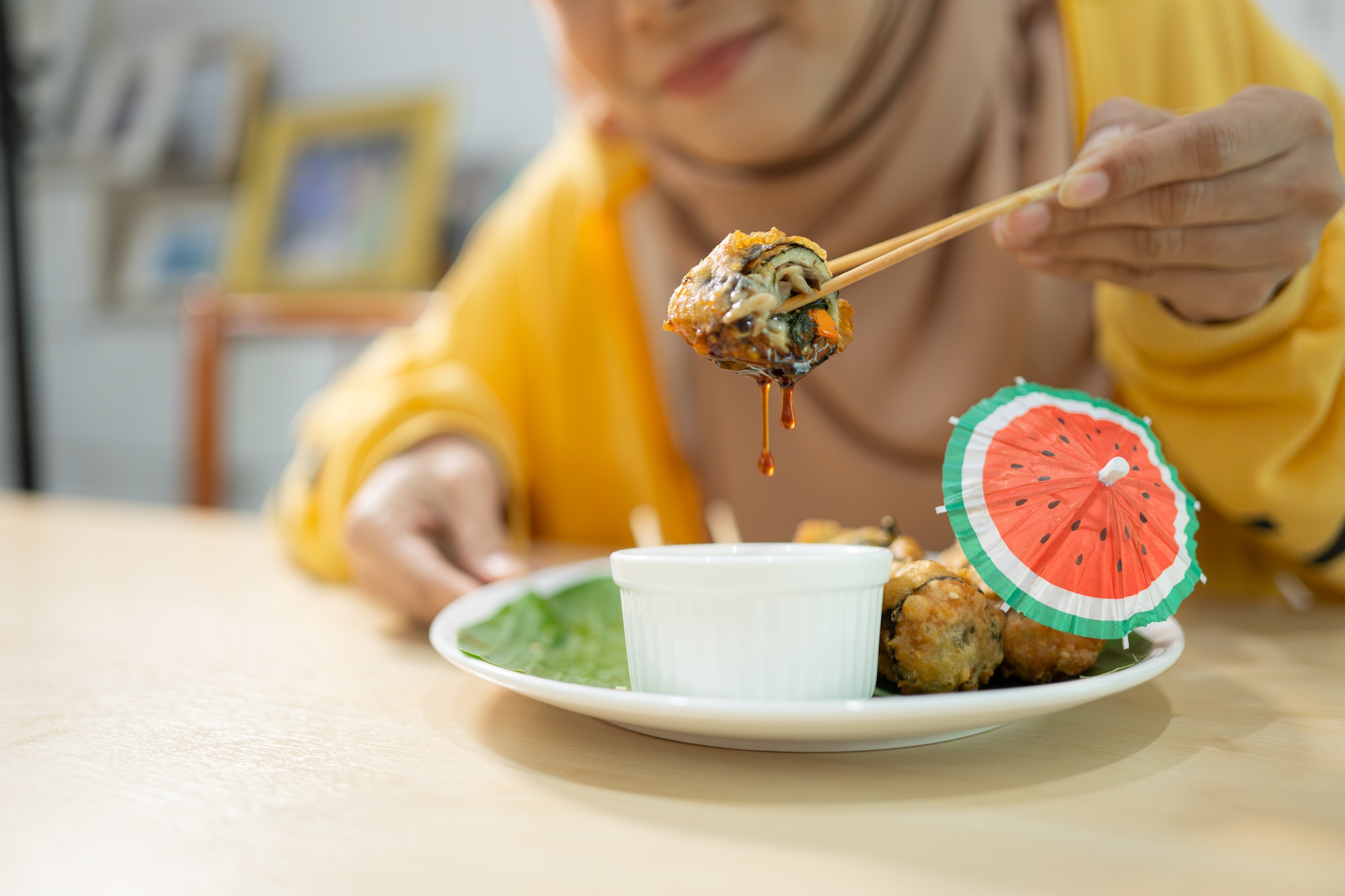Muslim girl eating mushroom sushi at the restaurant. Selective focus on sushi